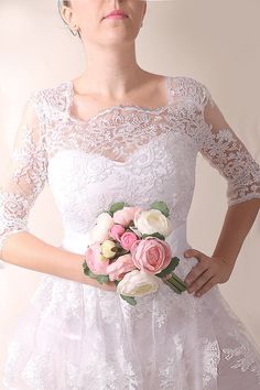 a woman in a white dress holding a pink and white flower bouquet with her hands on her hips