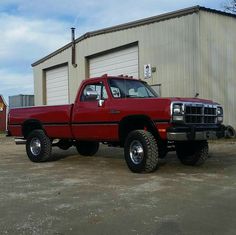 a red pick up truck parked in front of a building