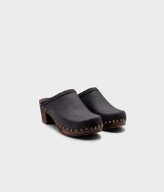 Made by skilled artisans in Sweden, these black nubuck clog mules feature a high heel and eye-catching stud detailing on the sides. From date nights to ladies' nights out, Rome delivers unparalleled style and confidence. Clog measurements:Heel height: 2 5/8” (6.5 cm)Toe height:﻿ 1 1/2″ (3.8 cm) Fit:NarrowLeather:Nubuck leatherClogs consist of:Base: European Lime Wood Sole: Rubber sole Fastening: Brass studs Leather Studded Slip-on Mules, Black Studded Mules With Round Toe, Black Leather Studded Mules, Clog Mules, Studded Clogs, Cork Sandals, Wooden Clogs, Clog Sandals, Date Nights