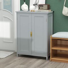 a small gray cabinet in the corner of a room with green walls and wooden floors