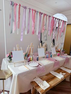 a long table is set up with pink and white ribbons hanging from it's ceiling