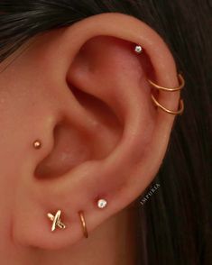 an ear with three different types of piercings on top of the ears and one is gold