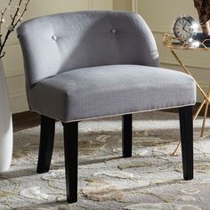 a gray chair sitting on top of a rug next to a vase with flowers in it