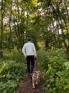 a man walking his dog on a path in the woods