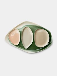 three oval dishes on a green plate