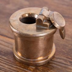 an antique brass toilet paper holder on a wooden table with the lid open and two metal knobs attached to it