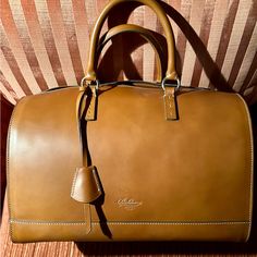 Nwt - Never Used - Boldrini Selleria Satchel Handbag. The Bag Measures 13” L X 10” H X 8 1/2” D. It Is Made Of Vacchetta / Calfskin Leather In Beautiful, Rich Camel Color. There Are Leather Side Gussets With A Full Two-Ended Zipper Opening At Either End. Gold Tone Hardware. This Is A Arm / Handbag. No Shoulder Strap. **Please Note** The Bag Has Two Minor Scratches Near Id Tag - Please See Photo. Possibly Occurred During Shipment - Does Not Detract From The Handbag. The Interior Has A 100% Red Co Brown Everyday Luxury Bag With Dust Bag, Top Handle Brown Travel Bag With Dust Bag, Brown Travel Bag With Dust Bag, Designer Cognac Satchel With Handle Drop, Designer Cognac Satchel, Luxury Travel Tote Bag With Dust Bag, Luxury Travel Tote With Dust Bag Included, Designer Brown Travel Bag With Top Handle, Designer Brown Top Handle Travel Bag