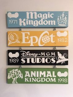 three disney world signs hanging on the wall in front of a white wall with an animal kingdom logo