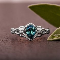 A handmade Celtic style platinum ring set with a beautiful, pear shaped Montana sapphire and small accent diamonds. The center stone is a 5mmX7mm natural Montana teal sapphire of high quality. Please note that the sapphires are natural stones and the exact shade may vary. The smaller stones are natural diamonds with a total carat weight of 0.06ct The ring is made with any of the available metals you select. All of the metals we use are 100% recycled. If you have any questions please feel free to Fine Jewelry Pear-shaped Sapphire Ring, Pear-shaped Birthstone Promise Ring, Teardrop Emerald Ring With Diamond Prong Setting, Pear-shaped Topaz Promise Ring With Accent Stones, Pear-shaped Sapphire Diamond Ring, Pear-shaped Sapphire Ring With Diamond Center Stone, White Gold Teardrop Moissanite Ring, Fine Jewelry Sapphire Ring With Pear Shape, Sapphire Pear-shaped Rings With Halo Setting