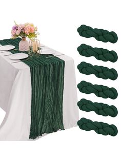 a table topped with plates and napkins covered in green cloth next to other place settings