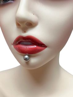 a mannequin's face with red lipstick and piercings on her nose