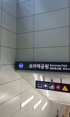 a subway station with signs and lights on the wall, in english and korean language