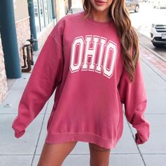 Show your school spirit with this varsity Ohio crewneck. Perfect for game days, to wear around campus, or to support your school from afar. Wear this Ohio varsity sweatshirt at the stadium or to tailagate. Luxurious comfort and style are what this unisex, garment-dyed sweatshirt is all about. It's made with 80% ring-spun cotton and 20% polyester and the fabric is 3-end garment-dyed, ring-spun, color-blast fleece with a 100% cotton face. Each sweatshirt comes with a relaxed fit, a rolled-forward College Team-colored Sweatshirt For Fall, Collegiate Pre-shrunk Sweatshirt For College, Varsity Team-colored Sweatshirt For College, Collegiate Crew Neck Top For Campus, University Red Sporty Sweatshirt For Game Day, Sporty University Red Sweatshirt For Game Day, University Red Cotton Sweatshirt With Letter Print, Pink Varsity Sweatshirt For College, Collegiate Sweatshirt With University Logo