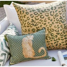 leopard print pillows on a white couch with green and yellow throw pillows, rolled up magazine, and coffee cup