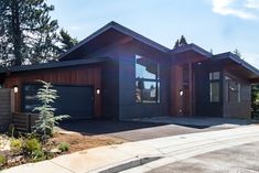 a house with two garages on the front and side of it, surrounded by trees