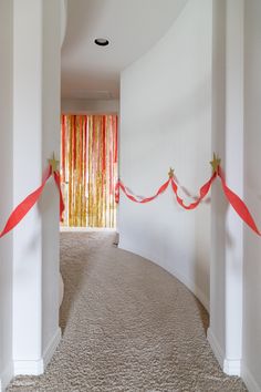 the hallway is decorated with red ribbon and gold star decorations on the wall, along with white pillars