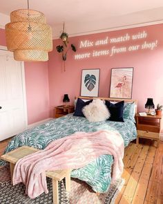 a bedroom with pink walls and palm leaves on the bedspread, two pictures hanging above the bed