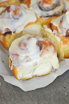 cinnamon rolls with icing sitting on top of paper