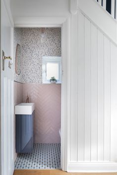 a bathroom with pink and blue tiles on the floor, sink and mirror in it