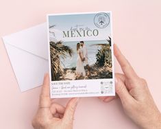 two hands holding up a postcard with an image of a couple on the beach