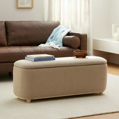 a living room with a couch, ottoman and coffee table in front of the window