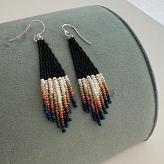 two pairs of beaded earrings sitting on top of a cushion