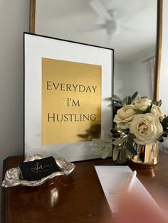 there is a vase with flowers on the table next to a framed poster that says everyday i'm husting