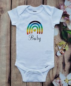 "Our rainbow short sleeve custom bodysuit is perfect for your precious miracle baby. Our Rainbow baby bodysuit is a beautiful gift to give as a baby shower gift or for someone special.  The Rainbow Baby bodysuit has a rainbow holographic vinyl that has been applied to the bodysuit. The pictures were taken at different angles so that the hologram effect can be seen. We use Gerber Onesies® made of 100% Cotton and all of our products are packaged in a clear protective bag. This listing is for the b Cute White Bodysuit For Gender Reveal, Cute Short Sleeve Bodysuit For Gift, Cute Short Sleeve Bodysuit As Gift, Multicolor Short Sleeve Cotton Bodysuit, Multicolor Cotton Short Sleeve Bodysuit, Unisex Short Sleeve Onesie As Gift, White Short Sleeve Bodysuit With Letter Print, White Personalized Bodysuit For First Birthday, Personalized White Bodysuit For First Birthday