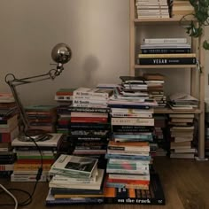 a pile of books sitting on top of a wooden floor next to a book shelf