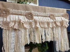 a window curtain with lace and flowers hanging from it's side