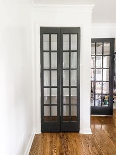 an empty room with two black doors and wood floors in the center is seen here