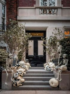 halloween decorations are on the steps in front of a building with a black door and white pumpkins