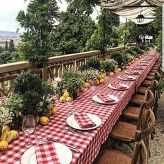 an outdoor dining area with red and white checkered table cloths, place settings and plates