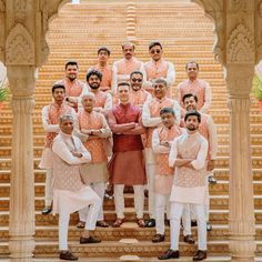 a group of men standing next to each other in front of some stairs and pillars