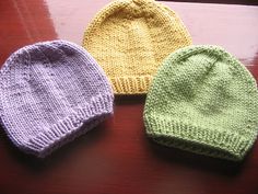 three knitted hats sitting on top of a wooden table