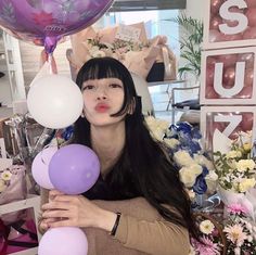 a woman with long black hair holding balloons