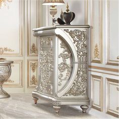 A luxurious antique silver finish with hand-brushed gold accents makes up the Sandoval collection. Surrounded by fine Rococo scrolls and floral ornament crowns with stylized ribbons. Fine finishing touches such as crystal-like buttons add a gleam to the pieces. The PU upholstery gives this collection a fresh contemporary touch. The chest features metal bottom drawer glides, which enhance stability and durability. These glides ensure smooth and consistent movement of the drawers, even when fully Metallic Furniture, Bedroom Organizer, Chest Bedroom, Cave Design, Man Cave Design, Large Dresser, Drawer Glides, Unique Furniture Pieces, Floral Ornament