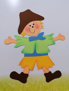 a paper cut out of a boy in a hat and green shirt standing on grass