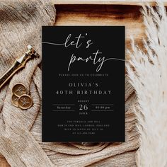 a black and white party card with a gold key on it next to some feathers