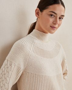 a woman in a white sweater poses for the camera