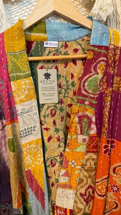 many different colored fabrics hanging on a wooden hanger in a store display case, with price tag