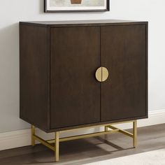 a brown cabinet with a gold circle on the door and a painting hanging above it