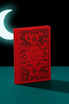 a red book sitting on top of a green table next to a white crescent moon