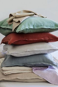 pillows stacked on top of each other in different colors and sizes, with one folded down