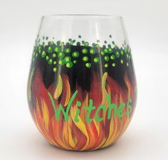 a wine glass painted with the words witches on it and flames coming out of it