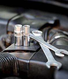 two wrenches are sitting on the hood of a car