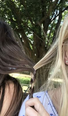 two women with long hair standing next to each other and one has her hair pulled back