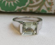 ✦✦ 8x10mm emerald cut  Green Amethyst is prong set in Sterling silver. ✦✦ Band width is approximately 3.37mm at the widest point by the stone and 1.54mm at thinnest point in the back.  This will be sent from Oslo  Introducing our exquisite 8x10mm green amethyst sterling silver ring, featuring a stunning emerald cut prasiolite stone. This ring is the perfect addition to any jewelry collection, offering a unique and timeless look that is sure to turn heads. Crafted from high-quality sterling silver, this ring boasts a lustrous and durable finish that will stand the test of time. The 8x10mm green amethyst stone is the centerpiece of this piece, showcasing a vivid and vibrant green hue that is truly captivating. The emerald cut of the prasiolite stone allows for maximum light reflection, creat Classic Green Amethyst Ring As Gift, Classic Green Amethyst Ring Gift, Classic Green Amethyst Ring For Gift, Classic Amethyst Ring With Rectangular Stone For Gift, Classic Amethyst Ring With Rectangular Stone, Sterling Silver Emerald Ring With Square Cut As Gift, Classic Green Amethyst Jewelry For Gift, Square Cut Emerald Ring In Sterling Silver, Silver Amethyst Ring Emerald Cut For Gift