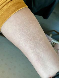 a person with a tattoo on their arm that has white flowers and leaves drawn on it