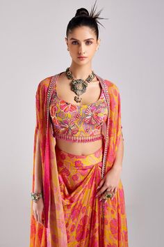 Pink foliage print cape in an asymmetric silhouette. Comes with matching sequin detailed crop top and dhoti skirt.
Components: 3
Pattern: Printed
Type Of Work: Foliage
Neckline: Cape: Open, Crop top: Round
Sleeve Type: Cape: Cape sleeves
Fabric: Modal, Georgette, Lining: Shantoon
Color: Pink
Other Details: 
Attached lining
Crystal tassels
Occasion: Sangeet,Cocktail - Aza Fashions Navratri Party Pre-draped Saree With Printed Motifs, Summer Festive Palazzo Set With Cape Sleeves, Silk Choli With Printed Motifs, Traditional Summer Sets With Cape Sleeves, Summer Sets With Sheer Dupatta And Cape Sleeves, Party Lehenga In Georgette With Printed Motifs, Party Lehenga With Printed Motifs In Georgette, Georgette Lehenga With Printed Motifs For Party, Festive Party Blouse With Printed Motifs